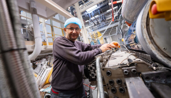 Zaandam fabriek thermovormen meneer kijkt lachend en sleutelt aan machine